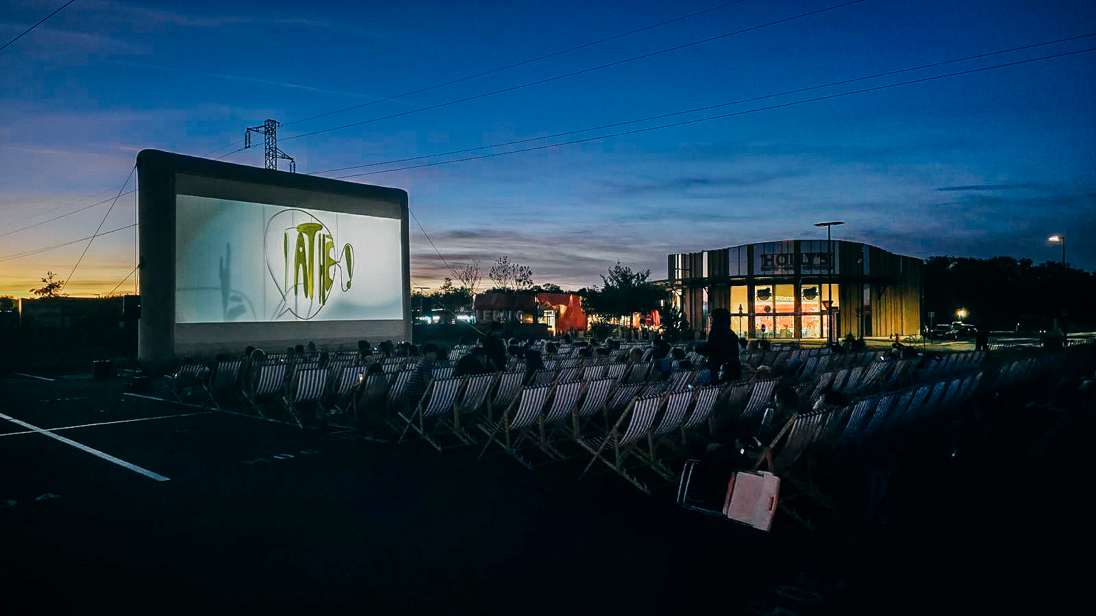 Le public installé dans des transats pour une séance de cinéma en plein air à Cap Saran au crépuscule